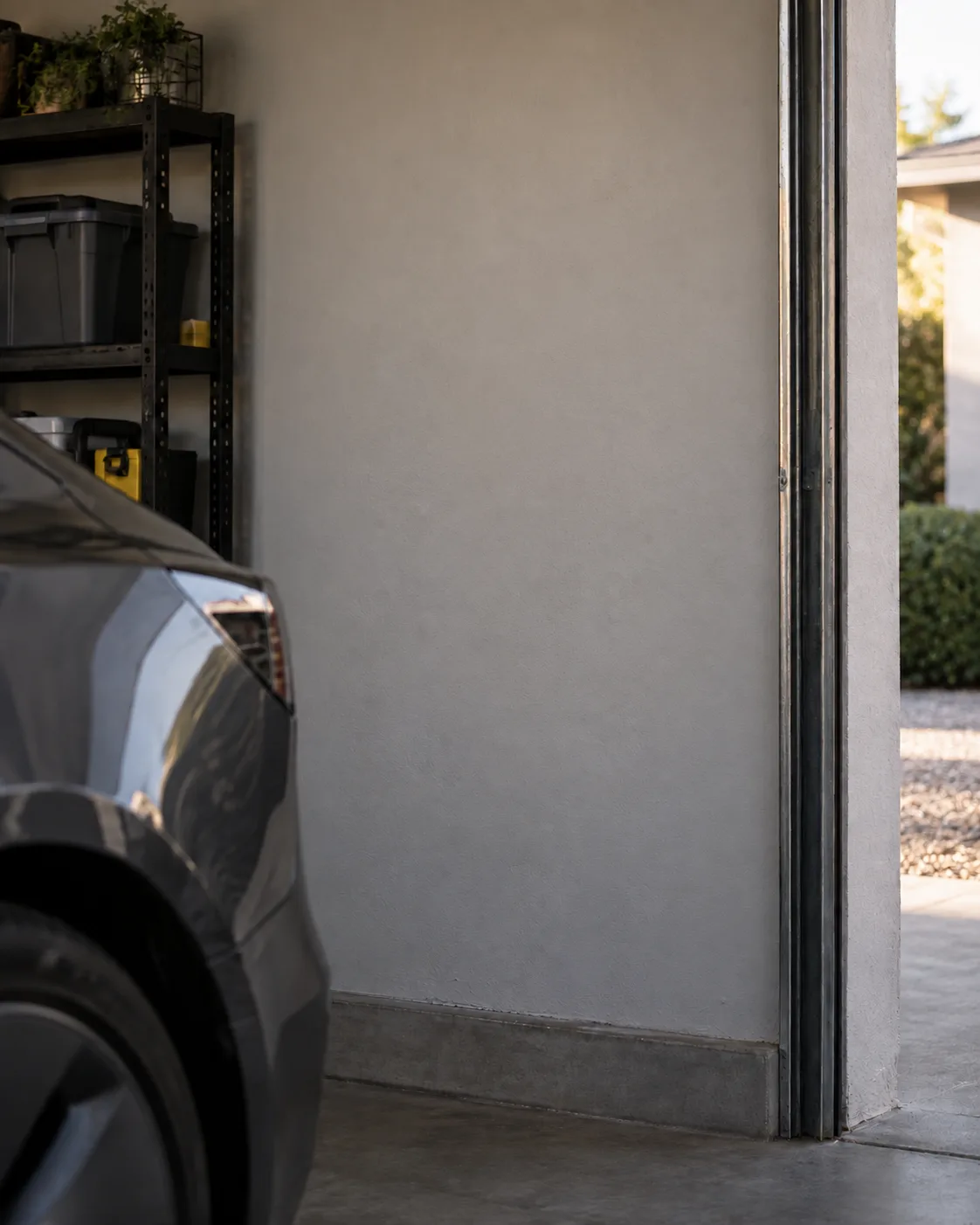 Illustration: a bare garage wall beside a parked car, with the garage door open to a driveway.